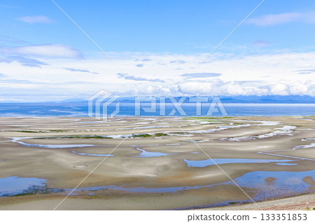Wide sandy beach at low tide with tidepools in sunny day. Wide sandy beach at low tide with tidepools in sunny day. 133351853