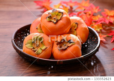Persimmon, a Japanese autumn fruit. The maple leaves in the background are artificial. 133352623