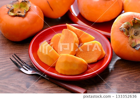 柿子,一種日本秋季水果。背景中的楓葉是人造的。 柿子,一種日本秋季水果。背景中的楓葉是人造的。 133352636