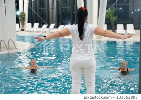 Instructor leading aquatic fitness training for group senior women in a swimming pool. Concept of health, exercise, wellness, water therapy, and active aging lifestyle 133352893