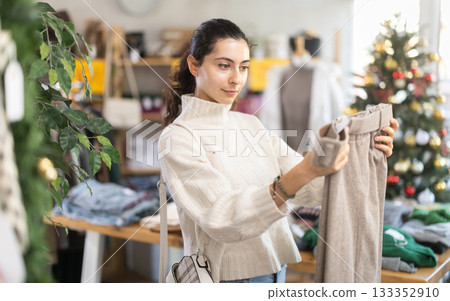 Armenian woman choosing warm pants in a store decorated for Christmas 133352910