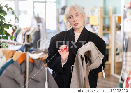 Regular customer senior woman chooses color and style of trousers 133352920