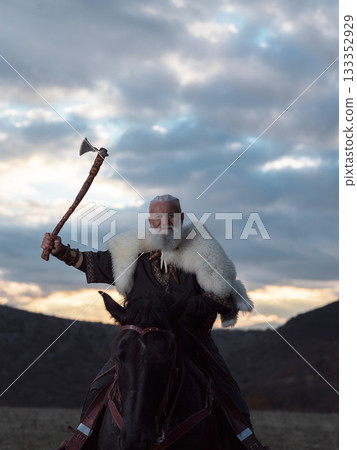 A fierce Viking warrior on horseback, wielding an axe, stands against a dramatic sunset sky with clouds and mountains, embodying strength, exploration, and ancient legend. A fierce Viking warrior on horseback, wielding an axe, stands against a dramatic sunset sky with clouds and mountains, embodying strength, exploration, and ancient legend. 133352929