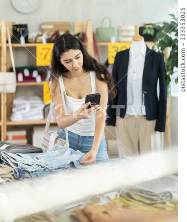 woman with long hair is eating at the counter with pants and scanning a barcode 133353025