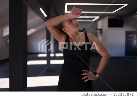 Workout session at a fitness center with a woman showing effort and focus in her exercise routine 133353071