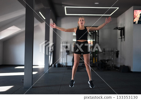 Young woman performing a jumping exercise in a modern gym during daylight Young woman performing a jumping exercise in a modern gym during daylight 133353130