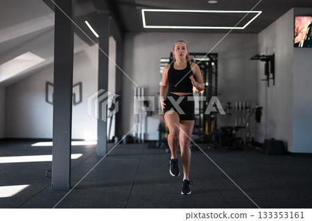 Female athlete performing high knees workout in a modern gym during the afternoon 133353161