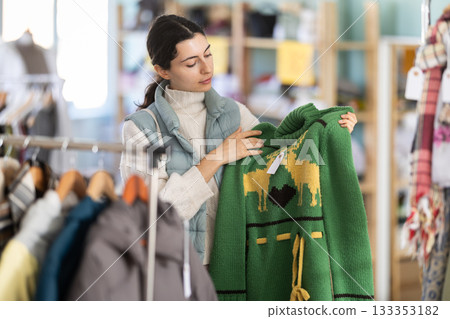 Armenian young pretty girl shopping sweaters in store. Sale of winter clothing collection Armenian young pretty girl shopping sweaters in store. Sale of winter clothing collection 133353182
