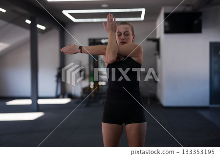 Woman practicing upper body stretches in a modern gym during a fitness session Woman practicing upper body stretches in a modern gym during a fitness session 133353195