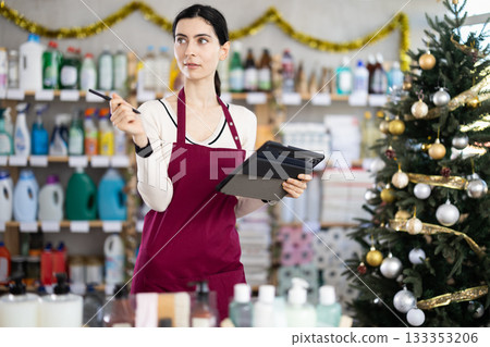 Female seller fills out a spreadsheet on a tablet about the availability of goods 133353206