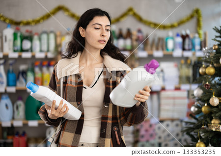 Young woman choosing laundry detergent in store during Christmas Young woman choosing laundry detergent in store during Christmas 133353235