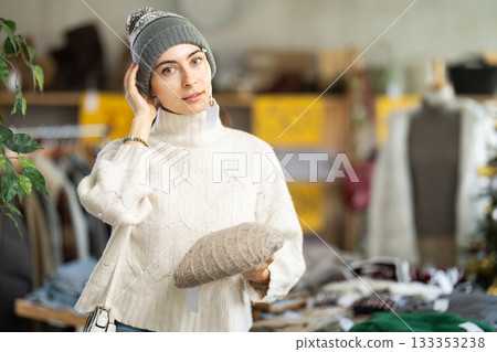 Armenian woman in warm clothes chooses a hat against the background of a Christmas tree Armenian woman in warm clothes chooses a hat against the background of a Christmas tree 133353238