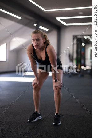 Woman resting after an intense workout session in a modern gym during daytime Woman resting after an intense workout session in a modern gym during daytime 133353280