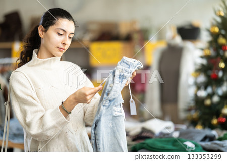 Armenian girl near showcase pick out and buying jeans, New Year eve 133353299