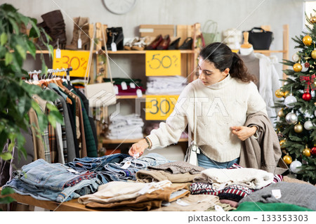 Armenian girl near showcase pick out and buying trousers, New Year eve 133353303