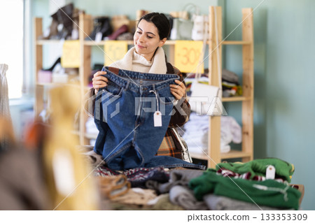 Elegance happy young girl buying jeans trousers in clothing store. Shopping and seasonal sales concept 133353309
