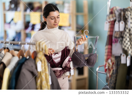 Girl chooses bra in fashionable clothing boutique 133353332