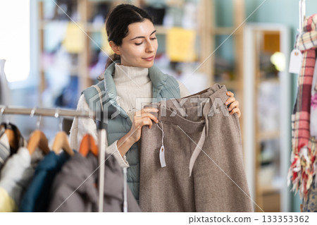 Armenian woman holding woolen pants in her hands against the background of the interior of a shop Armenian woman holding woolen pants in her hands against the background of the interior of a shop 133353362