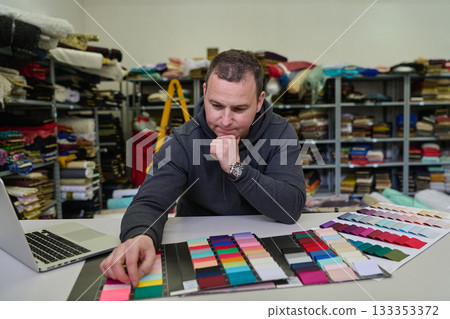 Man selecting fabric swatches in textile warehouse, designer choosing colors, material samples for fashion design, tailor at work, fabric store, textile industry Man selecting fabric swatches in textile warehouse, designer choosing colors, material samples for fashion design, tailor at work, fabric store, textile industry 133353372