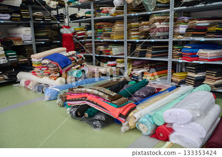 Fabric rolls and textiles on shelves in a warehouse, textile industry, cloth production, storage of fabrics, materials, and supplies in a fabric store, textile factory. Fabric rolls and textiles on shelves in a warehouse, textile industry, cloth production, storage of fabrics, materials, and supplies in a fabric store, textile factory. 133353424