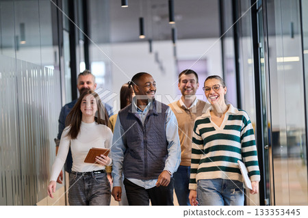 Group of confident professionals walking together through a bright modern office corridor. Concept of teamwork, diversity, success, collaboration, and positive workplace culture. 133353445
