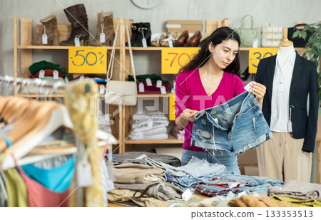 Woman with black hair choosing pants in a store 133353513