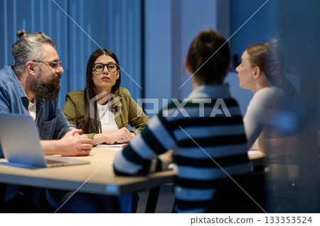 Group of diverse coworkers having a serious discussion around a conference table, led by a bearded male manager, representing teamwork, leadership, and strategy development in a modern business 133353524