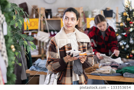 Armenian girl near showcase pick out and buying socks, New Year eve 133353654