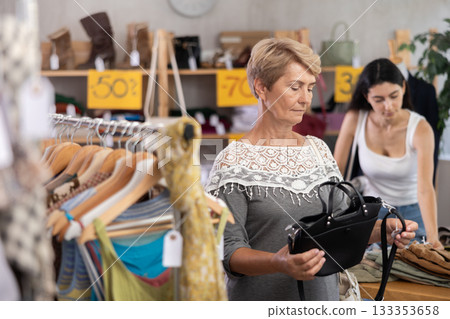 Senior woman customer elect leather handbag in store. Female client choosing something in background 133353658