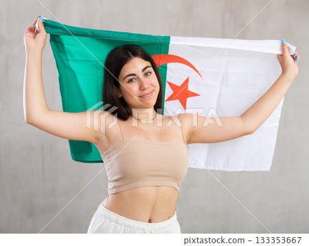 Happy young woman with flag of Algeria against unicoloured background Happy young woman with flag of Algeria against unicoloured background 133353667