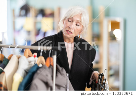 Elderly woman choosing a jacket and coat in a clothing store 133353671