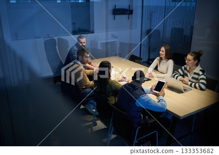 Diverse business team gathered around a table discussing analytics during a meeting in a modern office. Laptop screen shows charts and graphs, symbolizing teamwork, communication, and data driven Diverse business team gathered around a table discussing analytics during a meeting in a modern office. Laptop screen shows charts and graphs, symbolizing teamwork, communication, and data driven 133353682