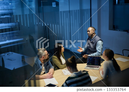 Diverse business team gathered around a table discussing analytics during a meeting in a modern office. Laptop screen shows charts and graphs, symbolizing teamwork, communication, and data driven Diverse business team gathered around a table discussing analytics during a meeting in a modern office. Laptop screen shows charts and graphs, symbolizing teamwork, communication, and data driven 133353764