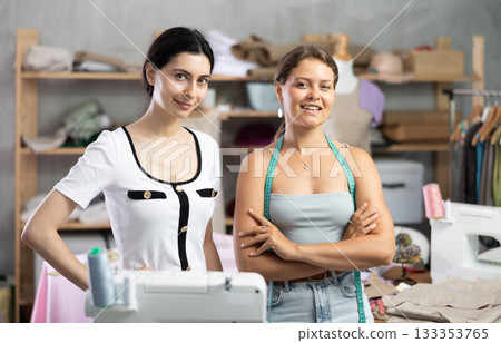 Smiling young professional seamstresses posing in workshop Smiling young professional seamstresses posing in workshop 133353765