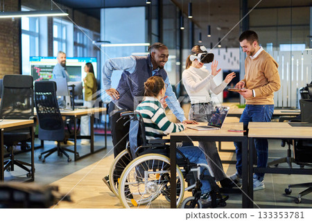 Diverse business team collaborating in a modern office environment. A woman in a wheelchair works on a laptop while colleagues explore virtual reality and digital tools, promoting innovation Diverse business team collaborating in a modern office environment. A woman in a wheelchair works on a laptop while colleagues explore virtual reality and digital tools, promoting innovation 133353781