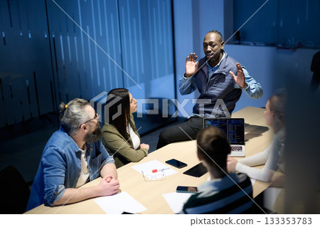 Diverse business team gathered around a table discussing analytics during a meeting in a modern office. Laptop screen shows charts and graphs, symbolizing teamwork, communication, and data driven 133353783