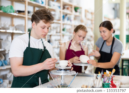 Young woman teaching teen boy and teen girl how to make ceramic cup 133353797