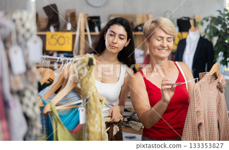Two women choosing clothes on sale in a store Two women choosing clothes on sale in a store 133353827