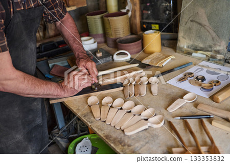 Craftsman carving wooden spoons in workshop, artisan shaping wood with hand tools, handmade crafts, traditional woodworking, small business, hobby project, craftsperson at work Craftsman carving wooden spoons in workshop, artisan shaping wood with hand tools, handmade crafts, traditional woodworking, small business, hobby project, craftsperson at work 133353832