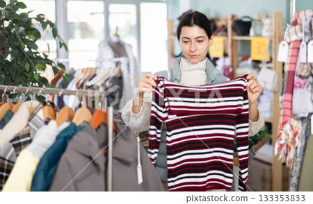 Armenian young pretty girl shopping sweaters in store. Sale of winter clothing collection Armenian young pretty girl shopping sweaters in store. Sale of winter clothing collection 133353833