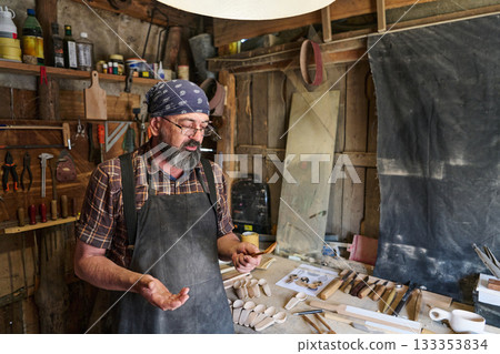 Craftsman in workshop creating wooden spoons, artisan woodworker carving spoons, handmade craftsmanship, small business owner, woodworking tools, rural lifestyle, traditional craft. Craftsman in workshop creating wooden spoons, artisan woodworker carving spoons, handmade craftsmanship, small business owner, woodworking tools, rural lifestyle, traditional craft. 133353834