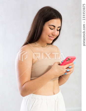 Young woman reading message on phone in studio 133353875