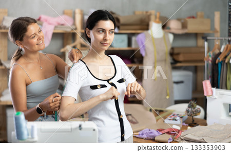 dressmaker takes measurements from the client 133353903