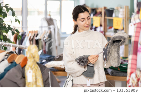 Armenian woman chooses a warm hat for the winter in the store 133353909