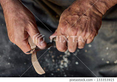 Close-up of craftsman hands carving wood with knife, woodworking and craftsmanship concept, skill and precision, wood carving process, hobby and art, handmade product photo. 133353915