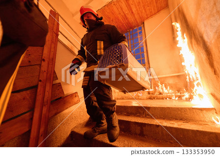 Brave firefighter carrying a rescued cat in a portable cage down smoky stairs during a building fire, symbolizing courage, compassion, and dedication to saving both human and animal lives in Brave firefighter carrying a rescued cat in a portable cage down smoky stairs during a building fire, symbolizing courage, compassion, and dedication to saving both human and animal lives in 133353950