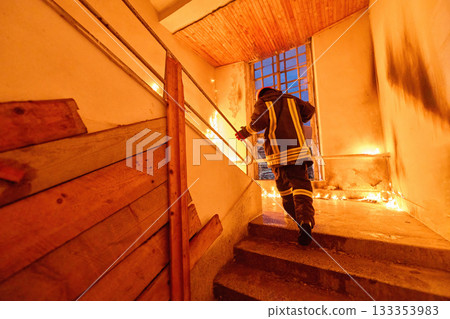 Brave firefighter carrying a rescued cat in a portable cage down smoky stairs during a building fire, symbolizing courage, compassion, and dedication to saving both human and animal lives in Brave firefighter carrying a rescued cat in a portable cage down smoky stairs during a building fire, symbolizing courage, compassion, and dedication to saving both human and animal lives in 133353983