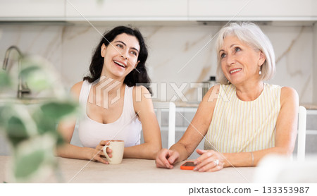 Young woman and elderly woman drinking tea in kitchen 133353987
