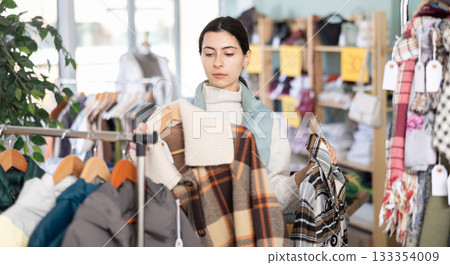 Elegance happy young girl choosing stylish warm coat or jacket in clothing boutique. Shopping and winter sales concept Elegance happy young girl choosing stylish warm coat or jacket in clothing boutique. Shopping and winter sales concept 133354009