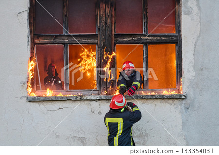 Firefighter rescuing a baby from burning building, fireman in action saving child, emergency situation, fire in house, danger, rescue operation, outdoor scene Firefighter rescuing a baby from burning building, fireman in action saving child, emergency situation, fire in house, danger, rescue operation, outdoor scene 133354031